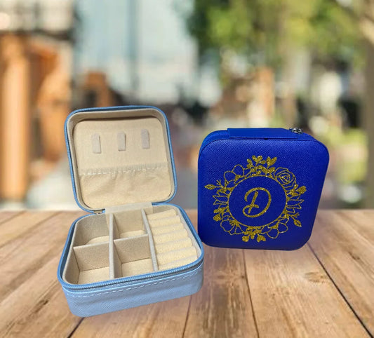 Blue jewelry case with open compartment and decorative lid on a wooden surface